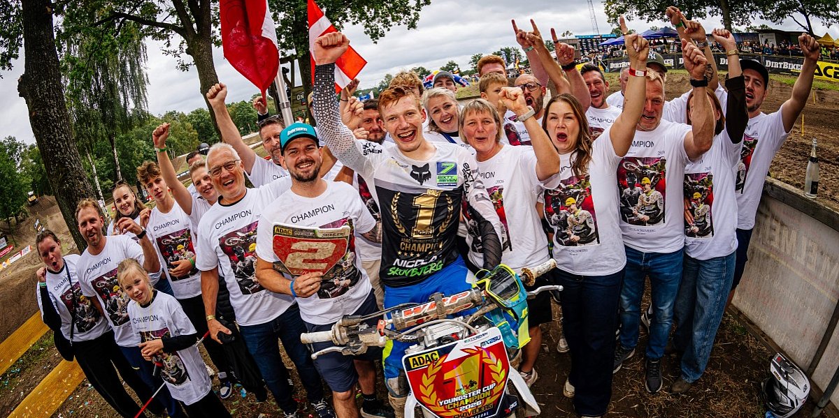 Skovbjerg sitzt freudig auf seinem Motorrad, und um ihn herum steht sein Team.