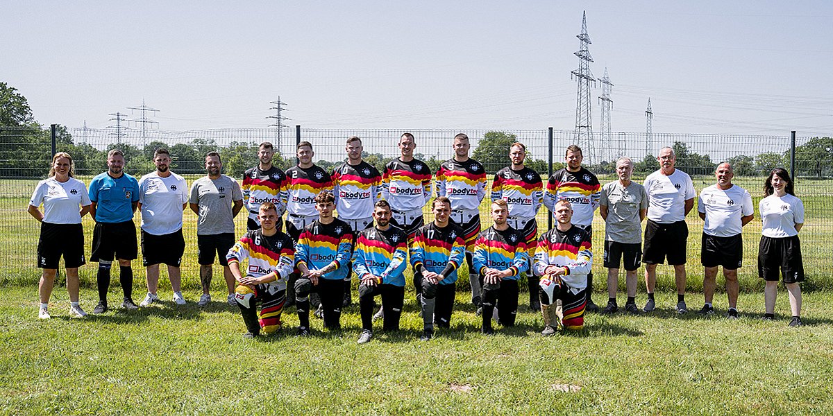 Motorsport Team Germany Motoball Senioren für die Motoball-EM 2026 Aufreihung des Motorsport Team Germany Motoball, 2 Reihen Personen mit deutschen Motoball Trickots stehen bzw. knien auf einer grünen Wiese unter freiem Himmel und schauen in die Kamera