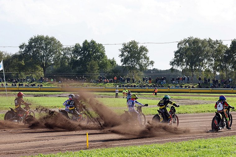 Deutsche Nationalmannschaft, Langbahn-Team-WM 2026, Roden Vier Langbahnfahrer mit den Startnummern 19, 20, 5, 21 und 4 fahren auf einer Sandbahn durch eine Kurve und wirbeln dabei Staub auf; im Hintergrund verfolgen Zuschauer das Rennen.