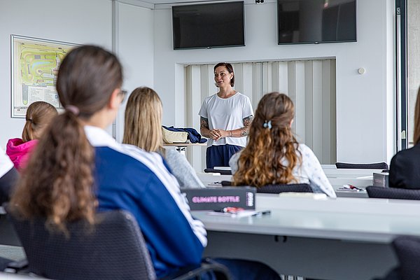 Lina van de Mars erklärt den Teilnehmerinnen im Pressecenter die Inhalte des Aktionstags, während die Schülerinnen aufmerksam zuhören.