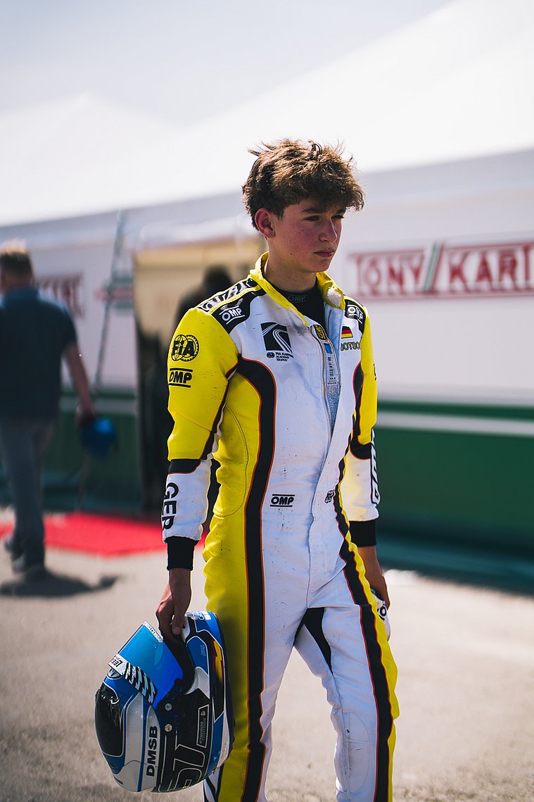 Stavros Tsotsos Francia, FIA Karting Academy Trophy Junior, Genk 2026 Stavros Tsotsos Francia steht in Rennanzug und mit Helm in der Hand vor dem Fahrerlager der FIA Karting Academy Trophy.