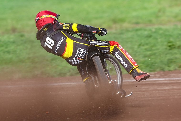 Deutsche Nationalmannschaft, Langbahn-Team-WM 2026, Roden Ein Langbahnfahrer mit der Startnummer 19 fährt im deutschen Teamtrikot stark geneigt durch eine Kurve und wirbelt dabei Staub auf.