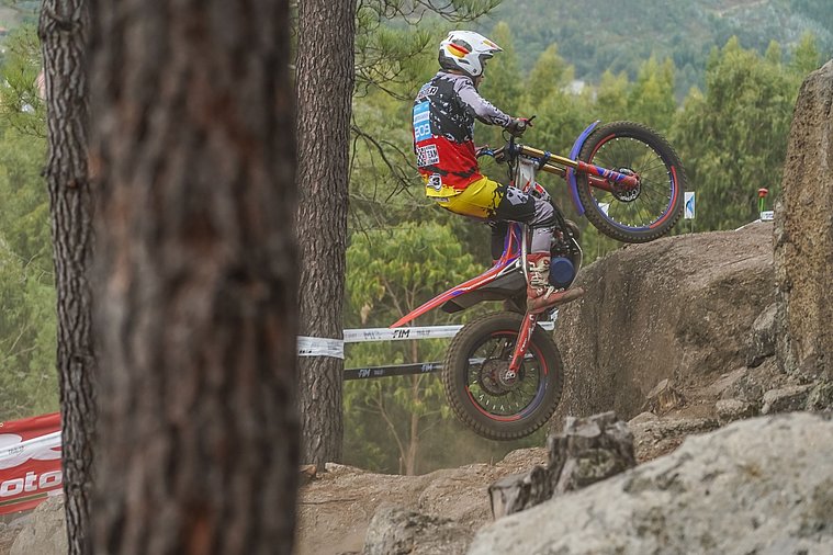FIM Trial der Nationen (TdN) 2026, Arteixo Deutscher Trial-Fahrer mit Deutschland-Helm und Teamkleidung überwindet auf seinem Motorrad eine felsige Passage im Wald.